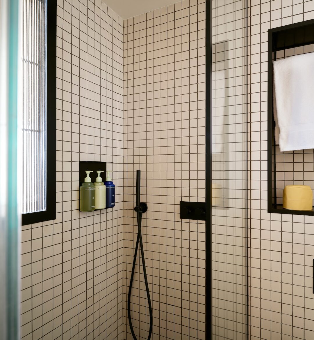 A modern bathroom featuring a walk-in shower with a glazed window and stylish white and black tile flooring.