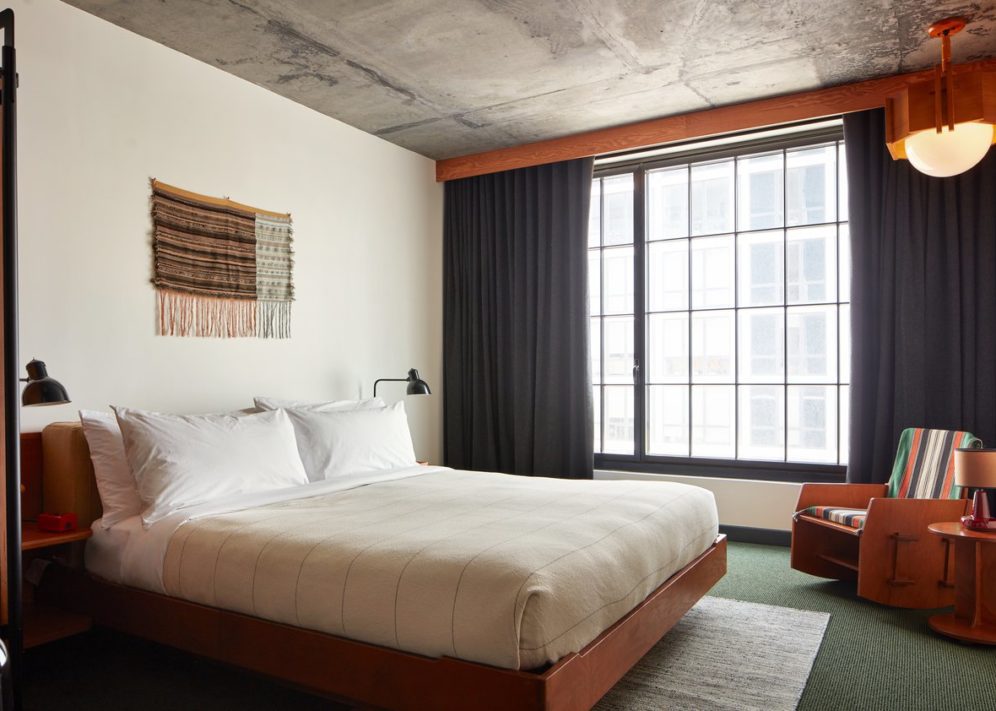 A room with modern styling featuring a striped rocking chair and concrete ceiling