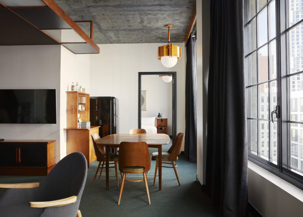 A table with 4 chairs sits between the bedroom and living room area