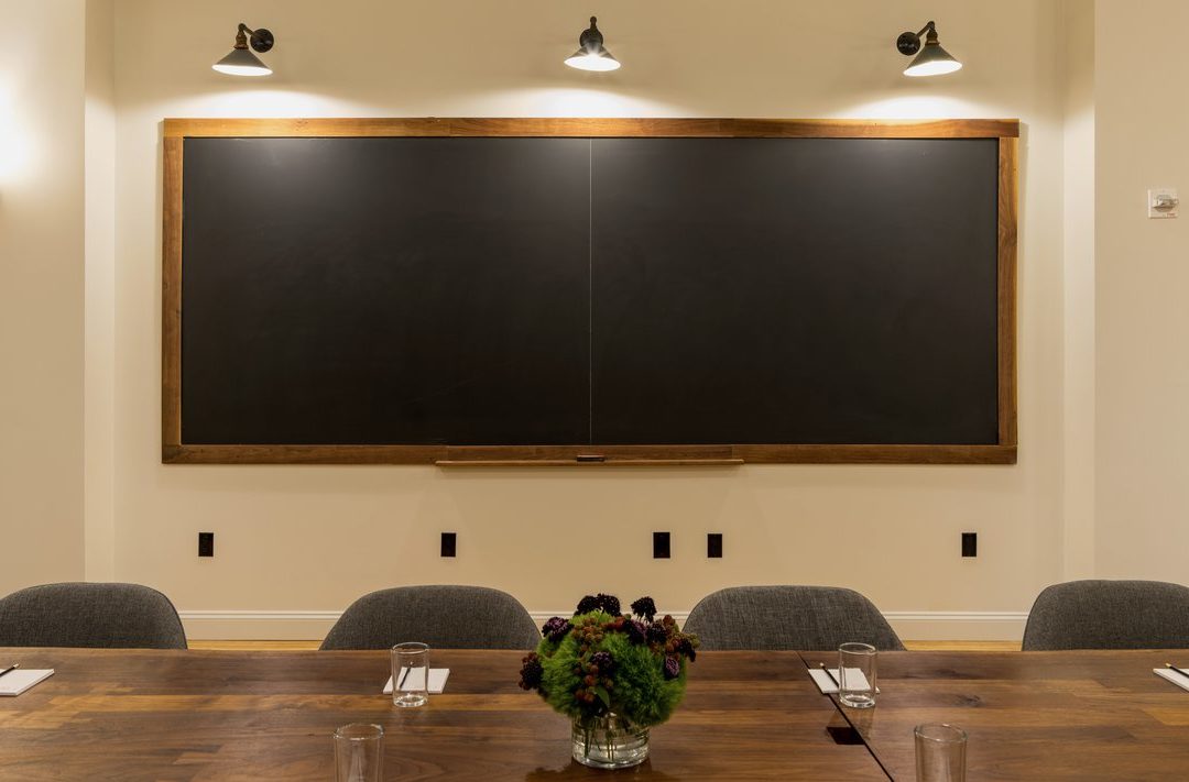 Ace Hotel New York meetings room with blackboard background and large dining table.