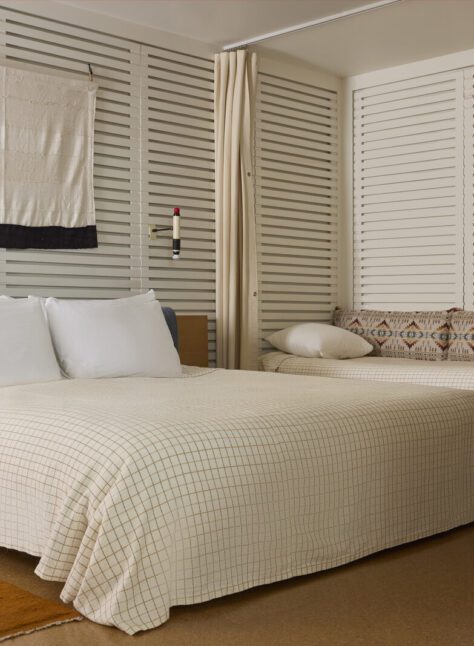 A large bed sits in the middle of the room, flanked by a radio on one side and twin beds against a wall on another
