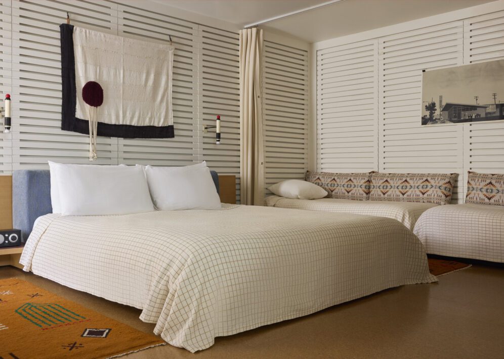 A large bed sits in the middle of the room, flanked by a radio on one side and twin beds against a wall on another