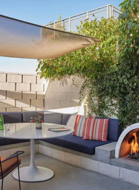 A private patio provides a sofa, table, and chair for outdoor relaxation; a small, semicircular fireplace provides warmth and ambiance