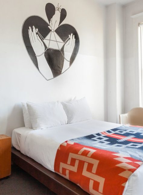 a bed with bright, ornate bedding is drenched in natural sunlight