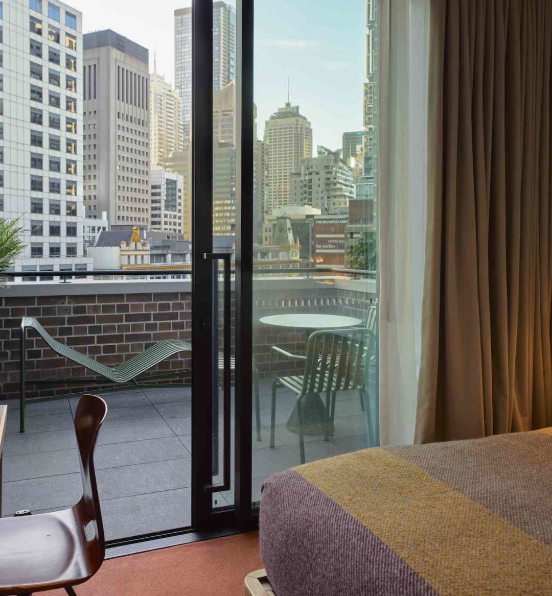 A floor to ceiling sliding glass door provides access to a patio with chairs and a table