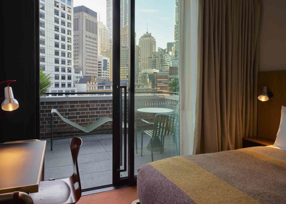 A floor to ceiling sliding glass door provides access to a patio with chairs and a table