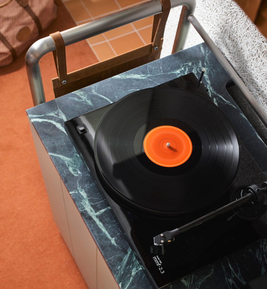 An active record player sits on top of black granite, spinning sounds for the room